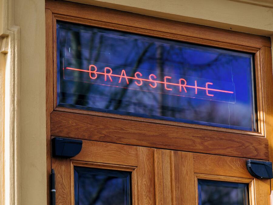 A wooden door with a neon sign that reads "BRASSERIE".