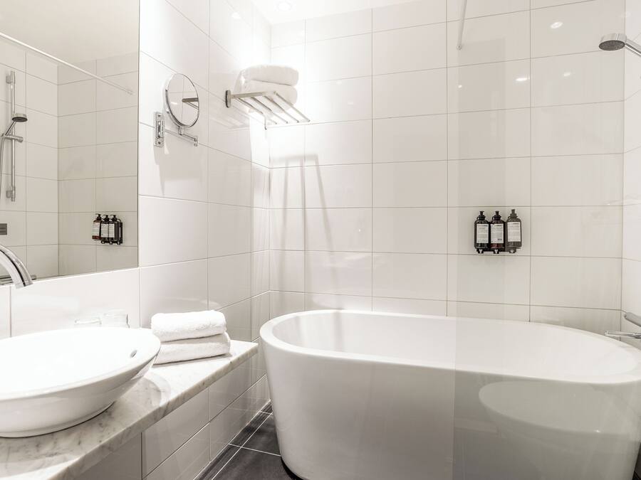 Un baño moderno con una bañera independiente, un espejo grande y un perchero de pared.