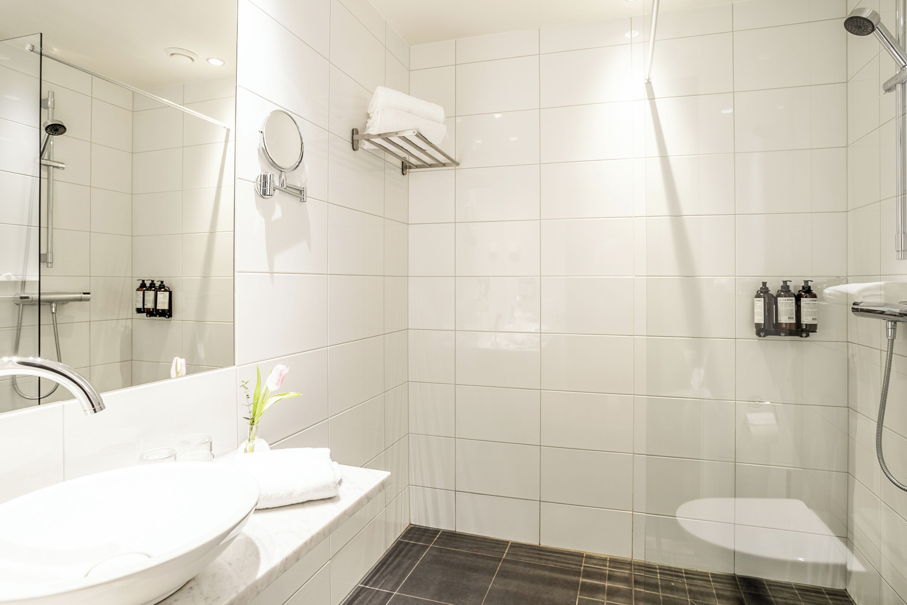 A modern bathroom with a large sink, mirror, and shower.