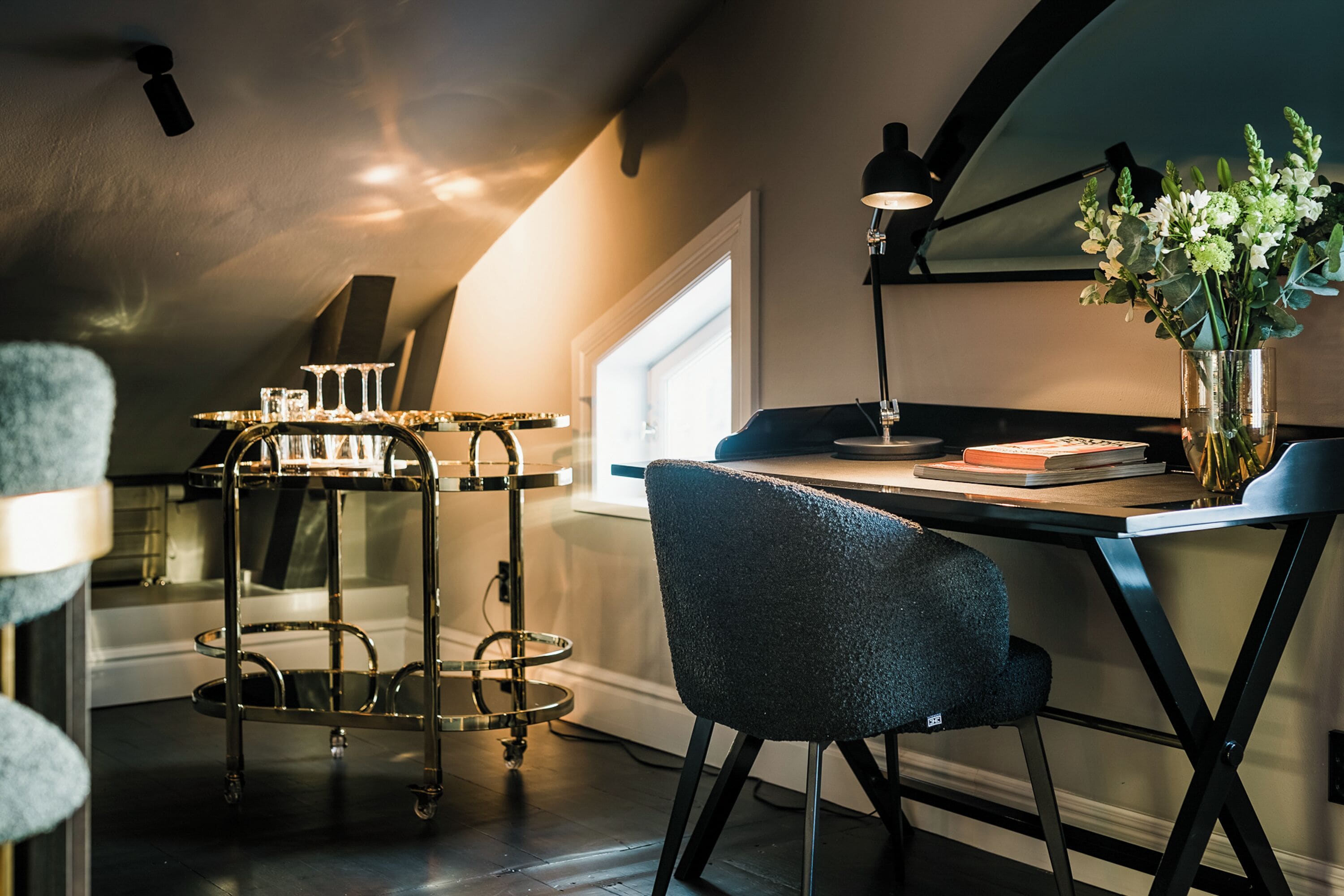 A modern kitchen with a dining table, a bar cart, and a chair.