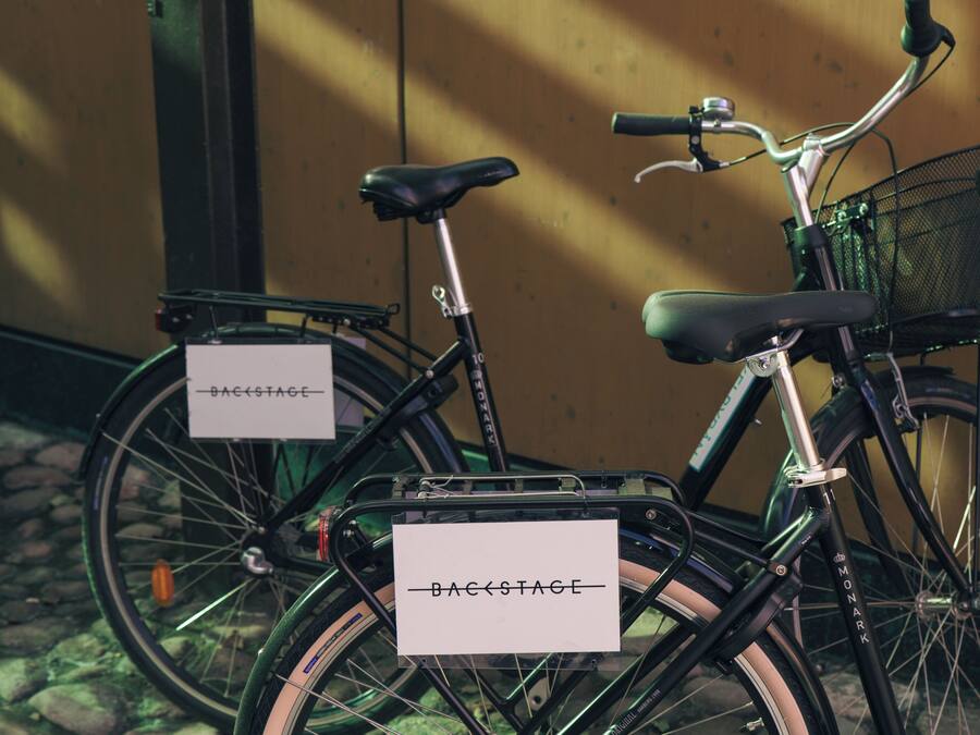 A bicycle with a basket and a sign that reads "BACKSTAGE."