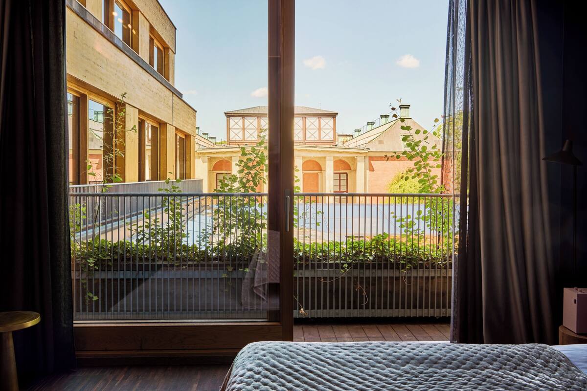 A room with a large window overlooking a courtyard with a building and greenery.