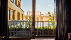 Una habitación con un amplio ventanal que da a un patio con un edificio y vegetación.