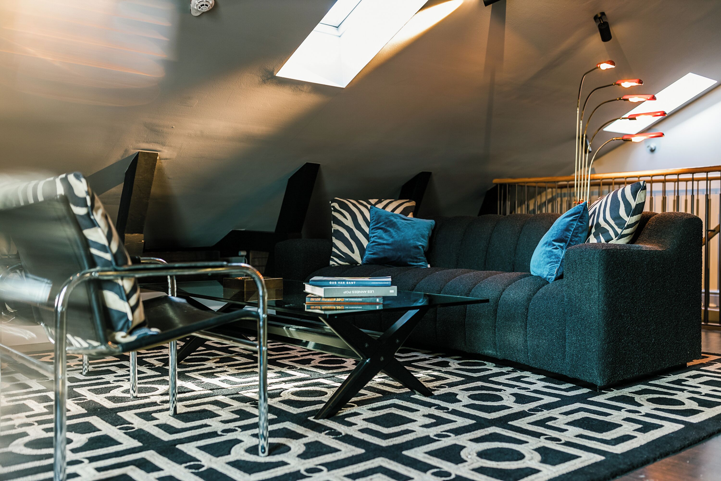 A modern living room with a sofa, armchairs, a coffee table, and a patterned rug.