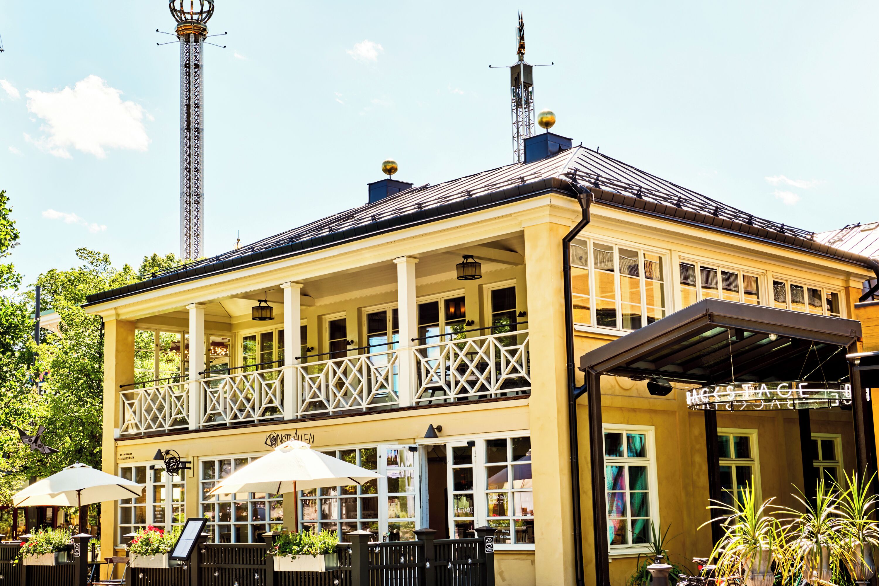 A yellow building with a balcony, outdoor seating, and a sign that reads "Hotel Eagle."