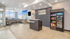 A reception area with a counter, seating, a refrigerator with snacks, and a cityscape view. - Clarion Pointe (Winnipeg)