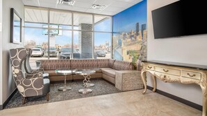 A hotel lobby with a large window, a sofa, a table, a TV, and a decorative console. - Clarion Pointe (Winnipeg)