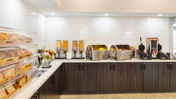 A breakfast bar with various food items and a waffle maker.