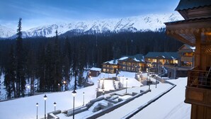 A snow-covered resort with multiple buildings, a stone staircase, and a mountainous backdrop. - The Khyber Himalayan Resort & Spa (Baramula)