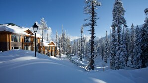 A snow-covered landscape with a row of wooden buildings, a street lamp, and snow-laden trees. - The Khyber Himalayan Resort & Spa (Baramula)