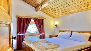 A wooden-framed bed with white bedding in a room with wooden ceilings and walls.