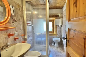 Une salle de bain avec douche, toilettes et lavabo.