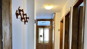 A hallway with wooden flooring, a ceiling light, and a door with a glass panel.