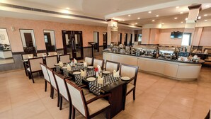 Un área de comedor con una mesa larga dispuesta para varios invitados, una estación de bufé y un televisor montado en la pared.
