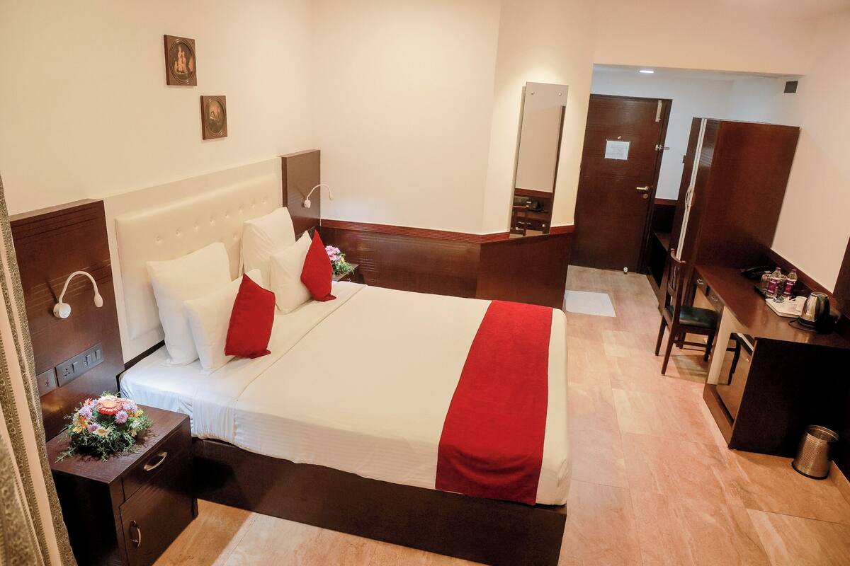 A hotel room with a large bed, a desk, and a mirror.