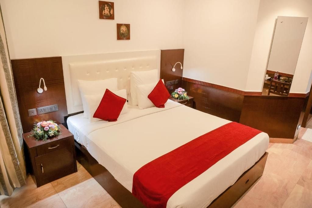 Habitación de hotel con una cama grande, dos mesitas de noche, un cabecero de madera y un espejo.