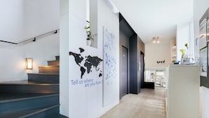 A modern interior with a staircase, a world map on the wall, and a sign asking for location. - Blu Monkey Bed & Breakfast Phuket (Phuket)