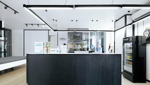 A modern reception area with a dark wooden counter, a beverage refrigerator, and a glass display case. - Blu Monkey Bed & Breakfast Phuket (Phuket)