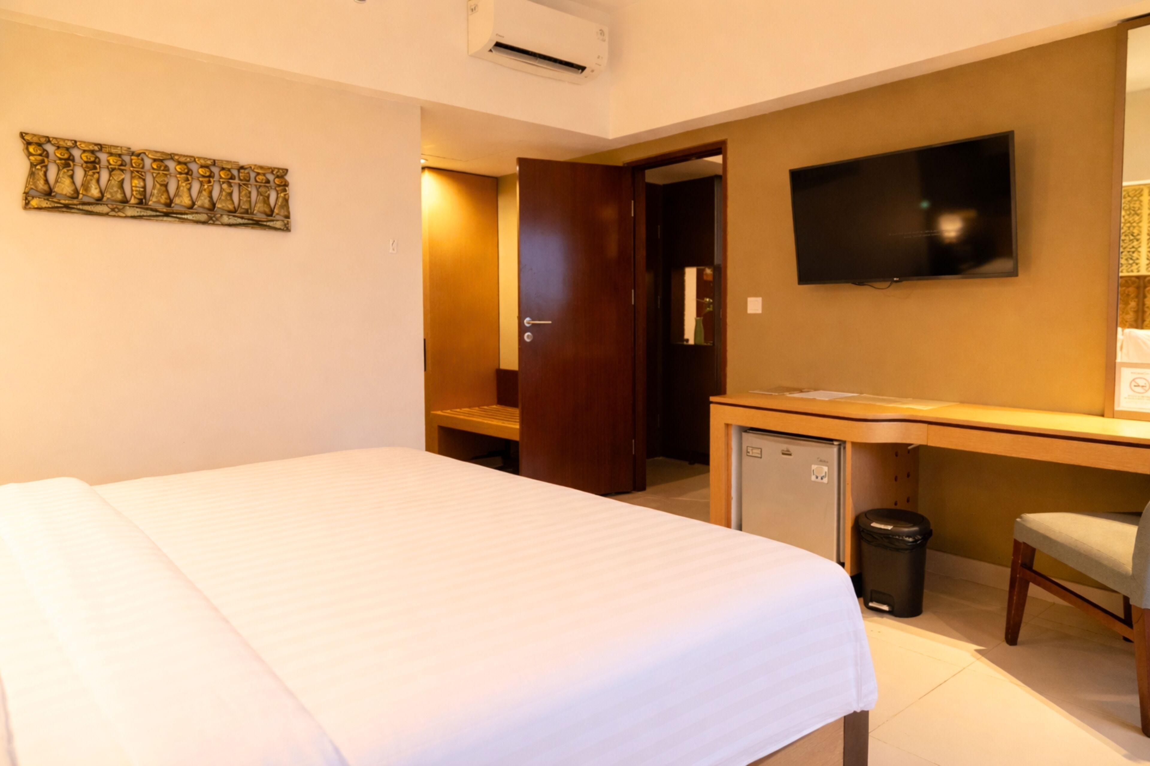 Une chambre d’hôtel équipée d’un lit, d’un bureau, d’une télévision et d’un petit réfrigérateur.
