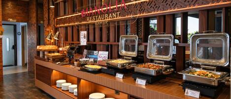 Montaje de bufé con diversas opciones de comida, un letrero que indica disponibilidad de alimentos sin gluten y el nombre del restaurante en la parte superior.