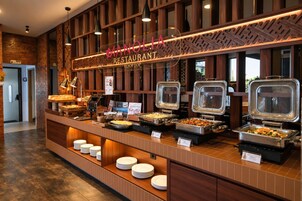 A buffet setup with various food options, a sign indicating gluten-free availability, and a restaurant name above.