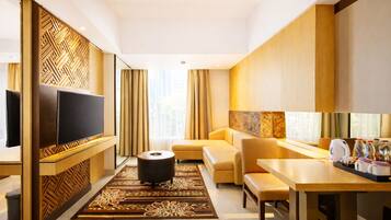 A modern hotel room with a flat-screen TV, a sofa, a dining table, and a coffee station.