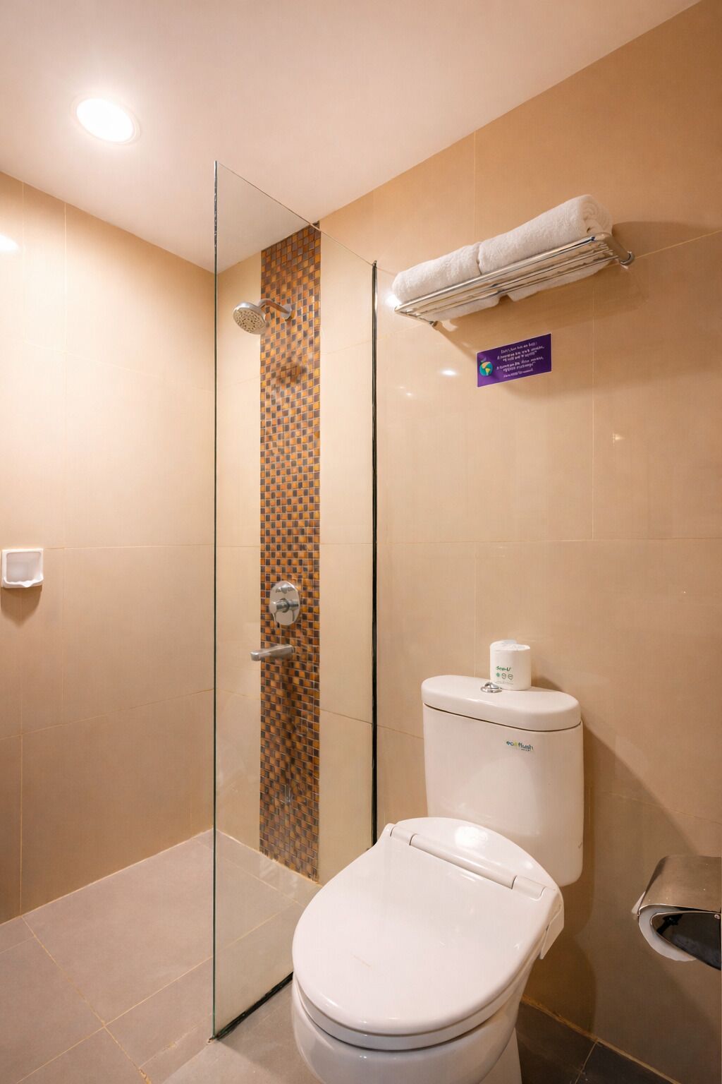 A modern bathroom with a glass shower enclosure, a toilet, and a hand dryer.