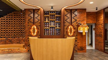A reception desk with a wooden finish, flanked by brick-patterned walls and recessed lighting.