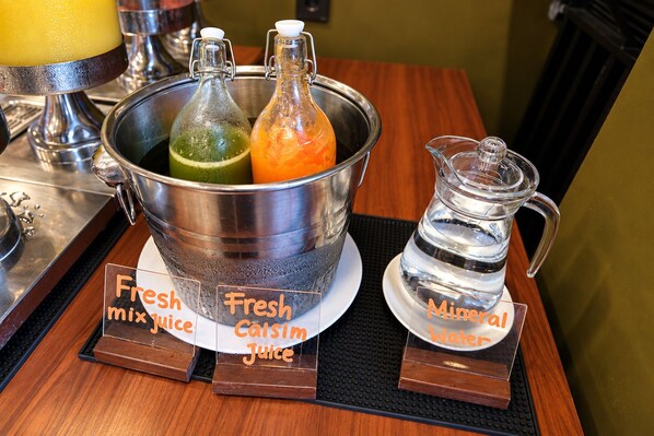 Zona de bar con un cubo metálico que contiene jugo fresco y una jarra de agua mineral.