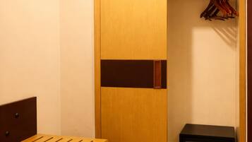 A walk-in closet with a wooden bench and shoe storage, a hanging rack, and a small electronic device on a shelf.