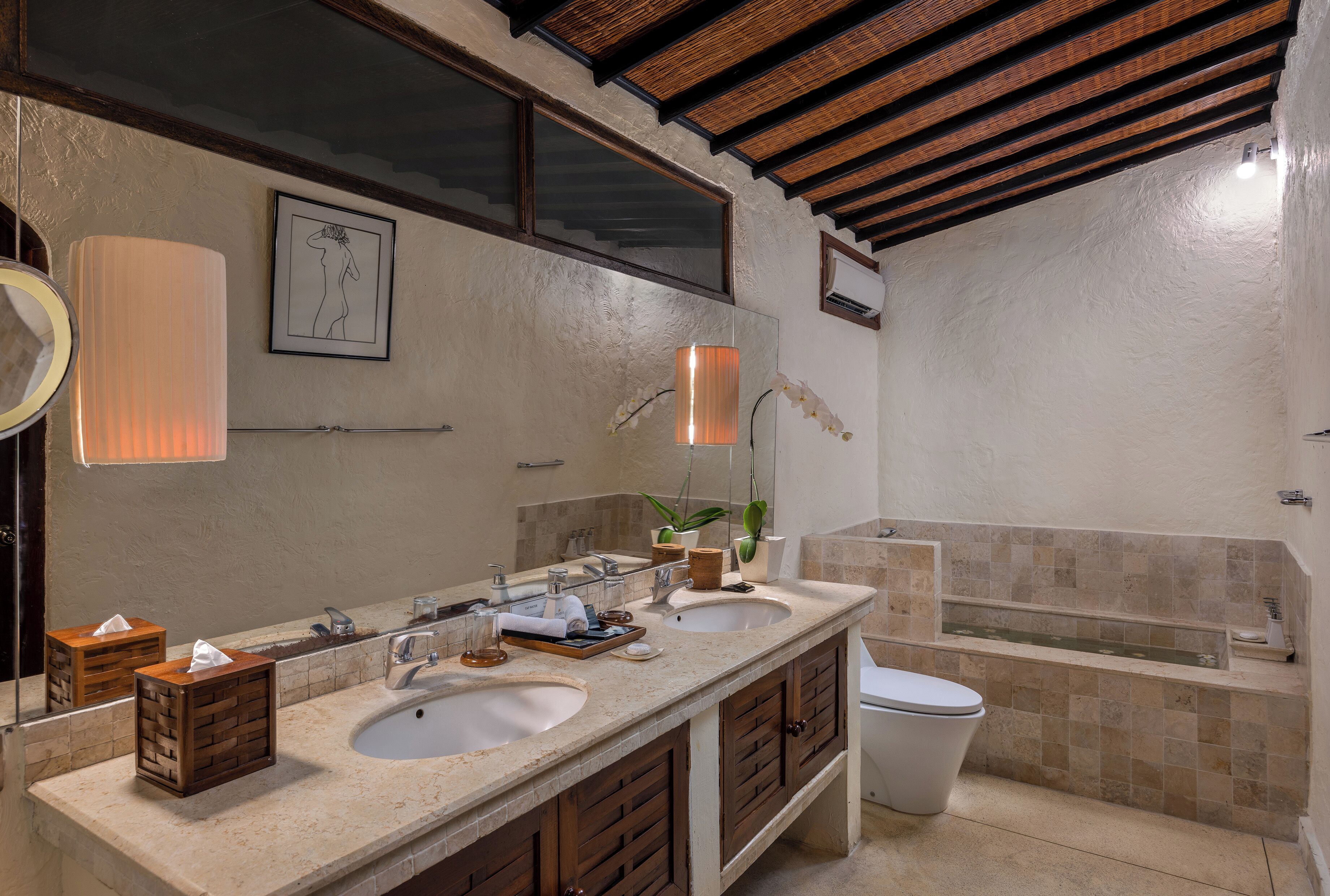 A bathroom with two sinks, a large mirror, a bathtub, and a toilet.