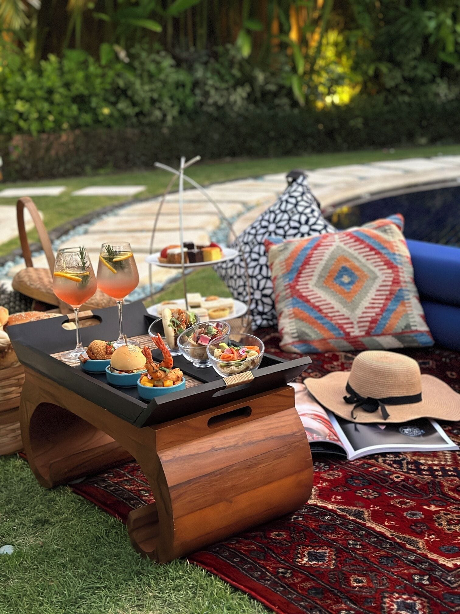 A wooden table with food and drinks, a patterned cushion, and a hat on a rug.