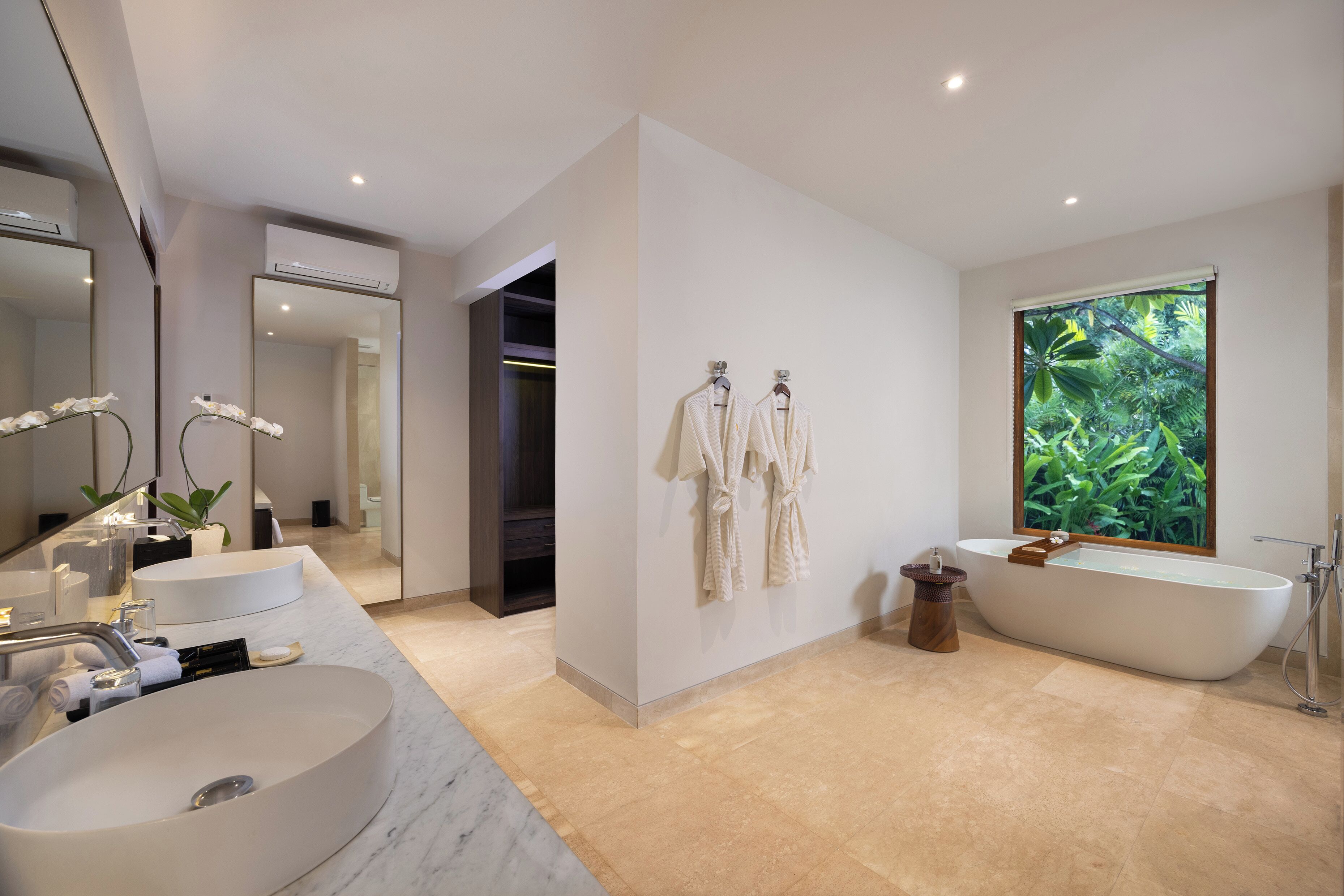 Un baño moderno con dos lavamanos, una bañera y un espejo grande.