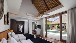 A hotel room with two beds, a TV, a wardrobe, and a view of a swimming pool. - Impiana Private Villas Seminyak (Seminyak)