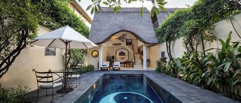 Una piscina con un símbolo yin-yang, rodeada por un patio con sillas y un paraguas.