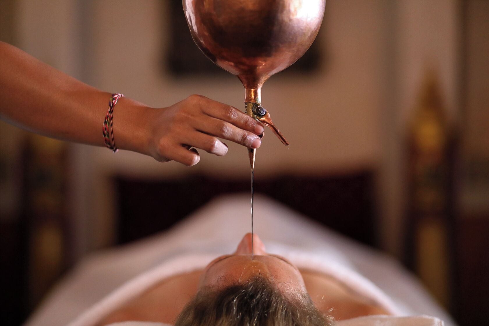 A person receiving a treatment with a copper vessel.