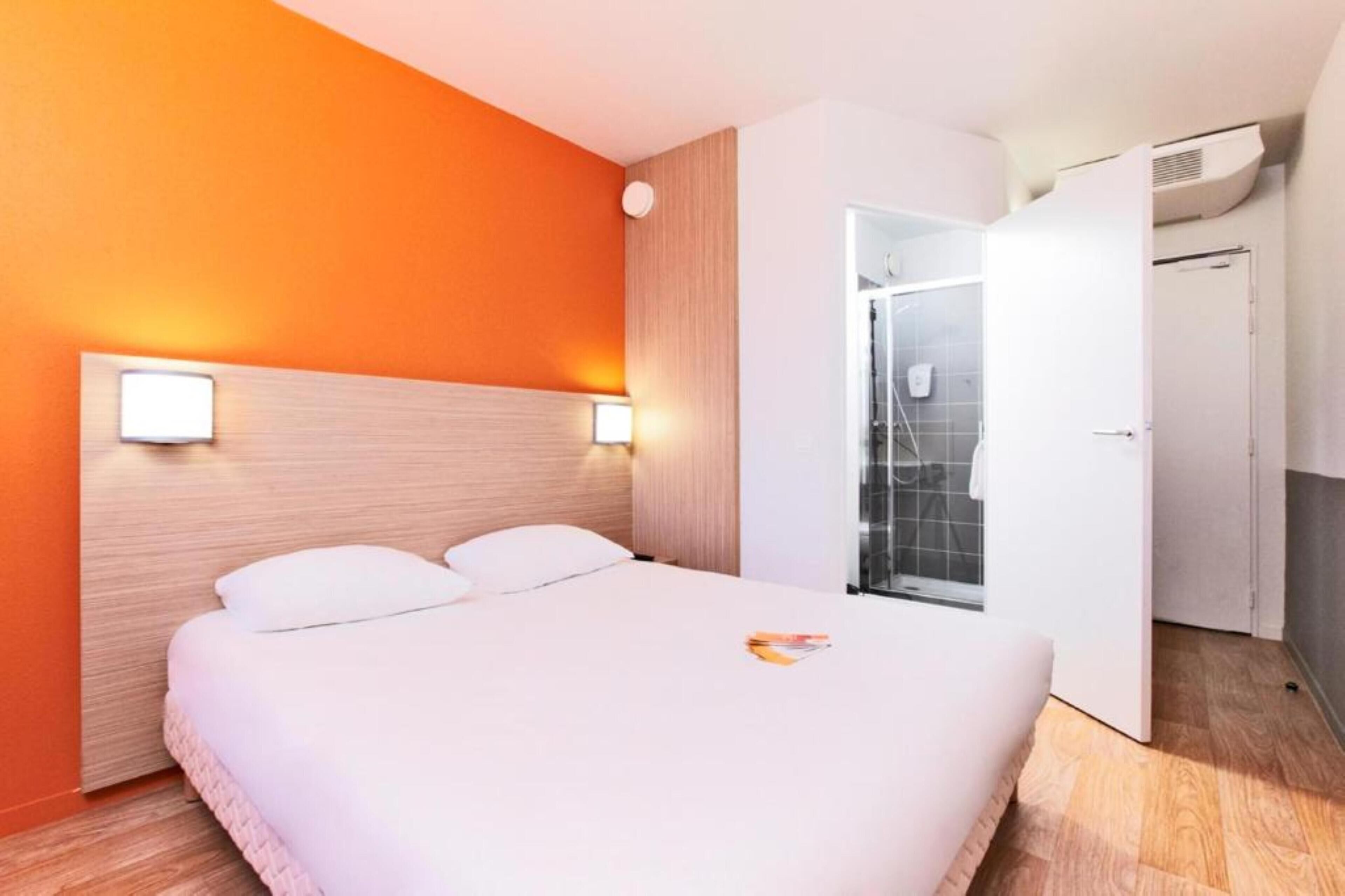 Una camera d'albergo con un letto, un armadio bianco e un angolo doccia.