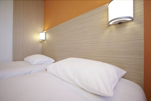 A hotel room with two beds, each with white linens and pillows. There is a wall-mounted light fixture above the beds. - Hôtel Première Classe Caen Nord - Mémorial (Saint-Contest)