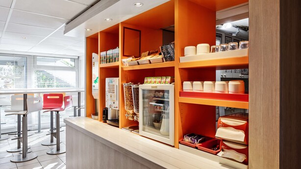 Un café moderno con mostrador, zona de estar y varios dispensadores de comida y bebida.