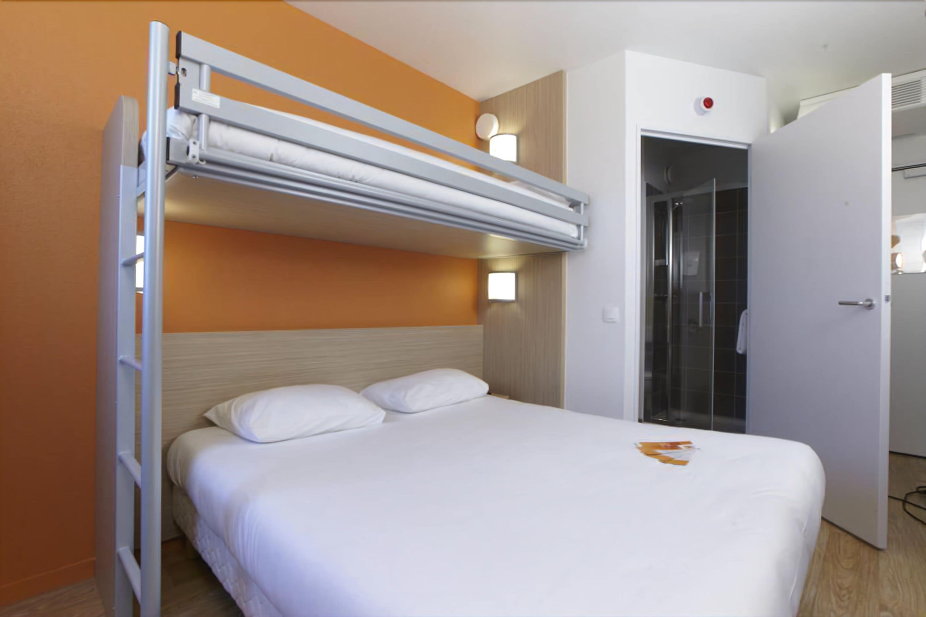Una cama individual con cabecera, un escritorio extraíble y un ventanal.