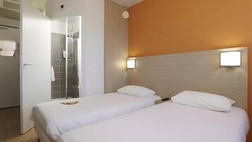 Habitación de hotel con dos camas, ducha y puerta que da al baño.