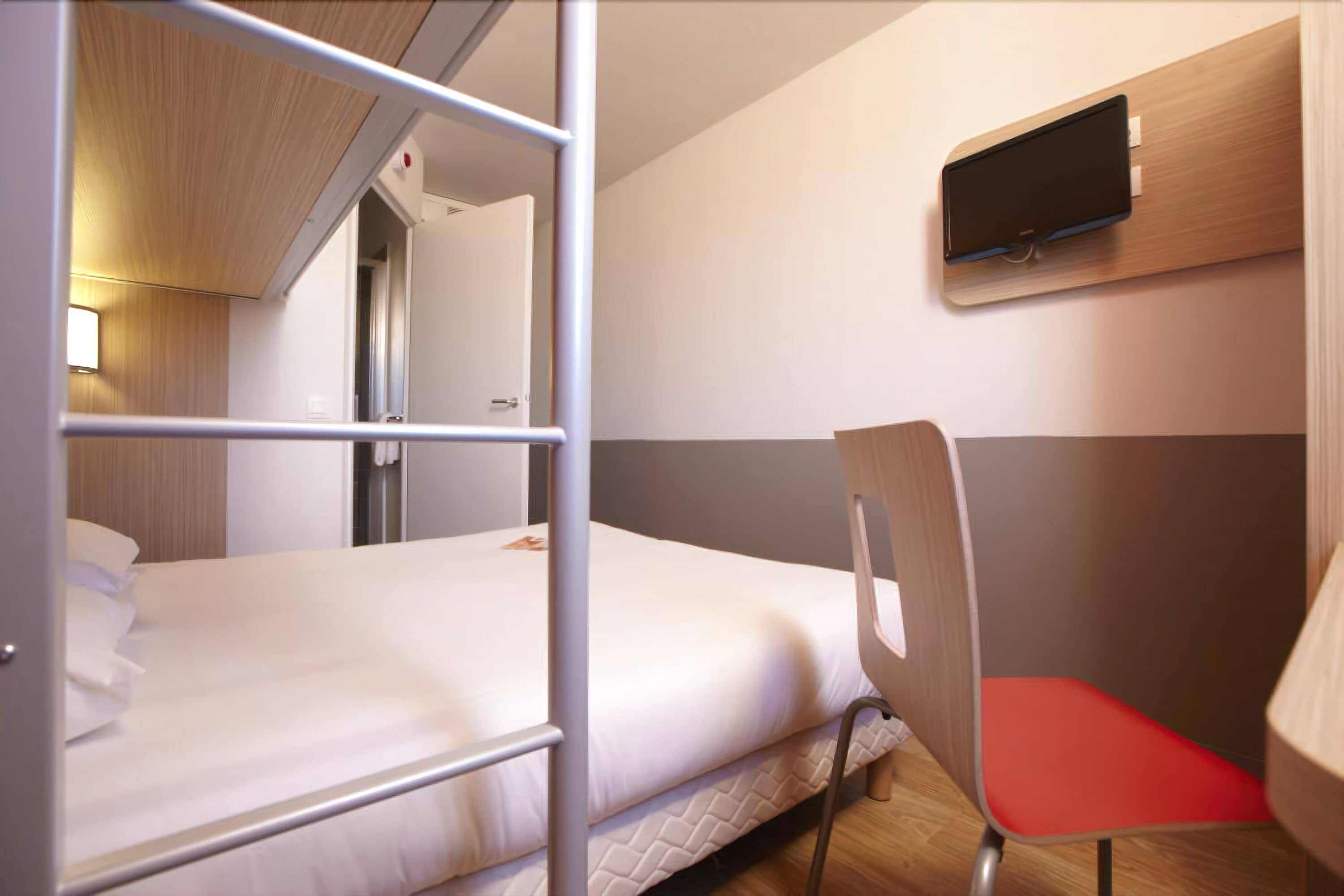 A bunk bed with a TV mounted on the wall above it.