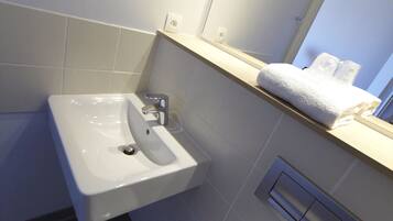 A bathroom with a white sink, a mirror above it, and a towel on the countertop.