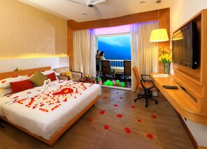 Une chambre d’hôtel avec un grand lit, un bureau, une chaise, une télévision et un balcon avec vue.