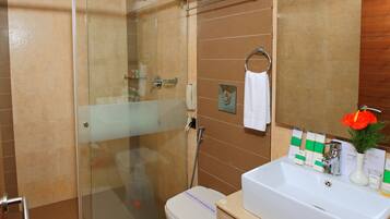 A modern bathroom with a glass-enclosed shower, a white sink with a mirror, and toiletries.