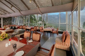 Un restaurant avec des tables dressées, des chaises et un canapé.