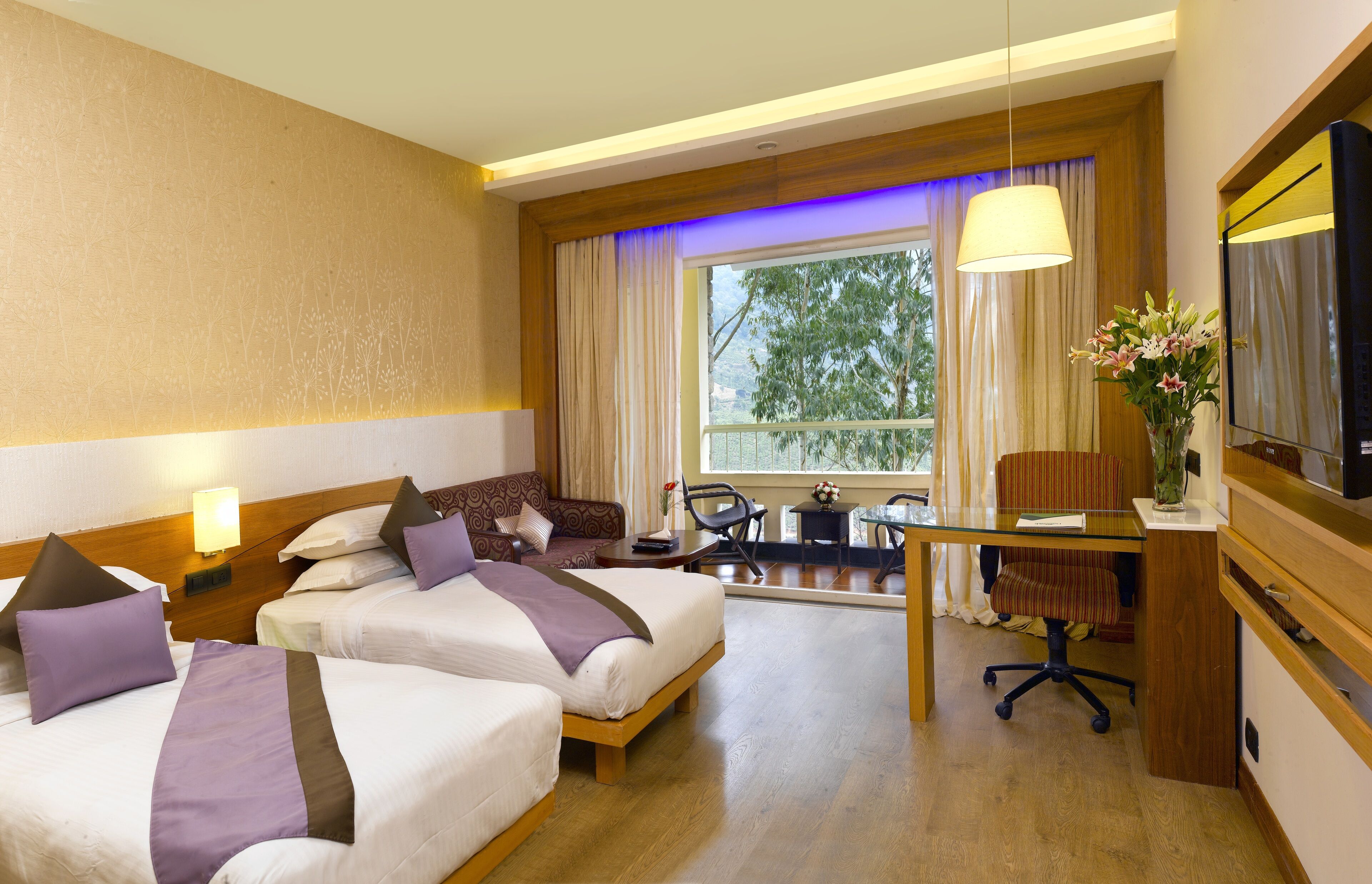 A hotel room with two beds, a desk, a chair, a TV, and a window with curtains.