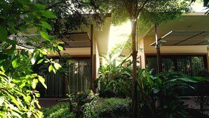A modern building with a covered outdoor area, surrounded by lush greenery and a stone pathway. - Ploykhumthong Boutique Resort (Bangkok)