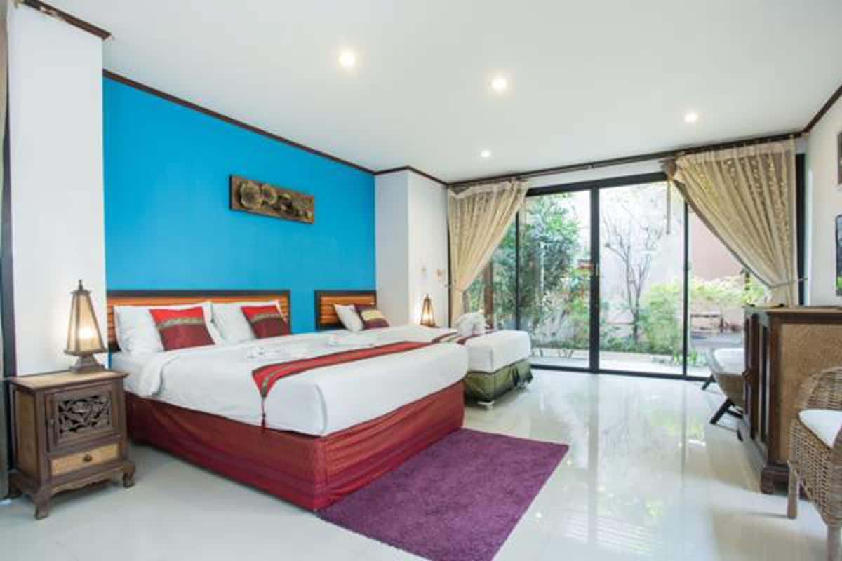 Un dormitorio moderno con una cama grande, una mesita de noche, una silla y vistas al exterior a través de un ventanal.