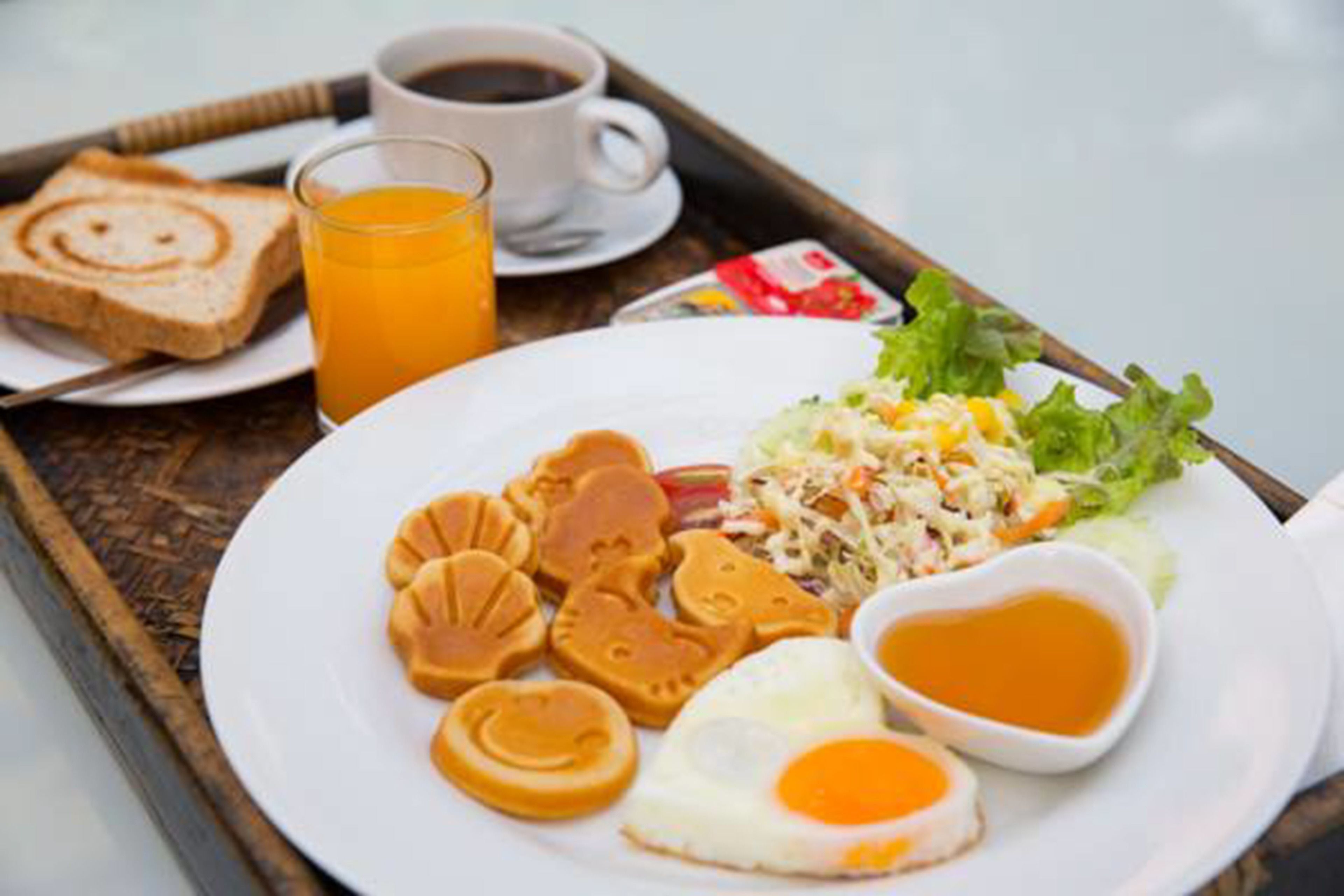 A breakfast tray with toast, orange juice, coffee, a plate with eggs, sausage, and a salad.